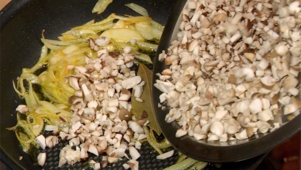 When the aroma grows stronger and the onion and garlic turn golden brown, add the bay leaf and the chopped mushrooms.
