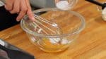 Coloca la yema de huevo en un tazón y agrega la mitad del azúcar. Usando un batidor de varillas, bate la mezcla de huevo por completo hasta que se vuelva de color claro, como se muestra.