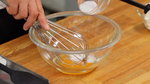 Place the egg yolk in a bowl and add half of the sugar. Using a balloon whisk, beat the egg mixture thoroughly until it turns a light color as shown.