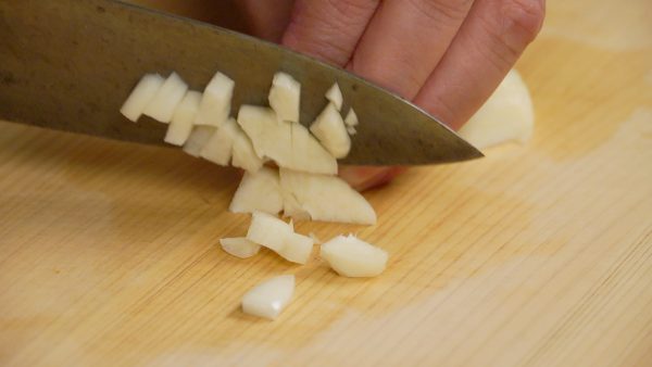 Cắt tép tỏi lớn làm đôi và ép vỡ nó bằng cạnh dao. Loại bỏ lõi và thái tỏi thành các miếng vừa.