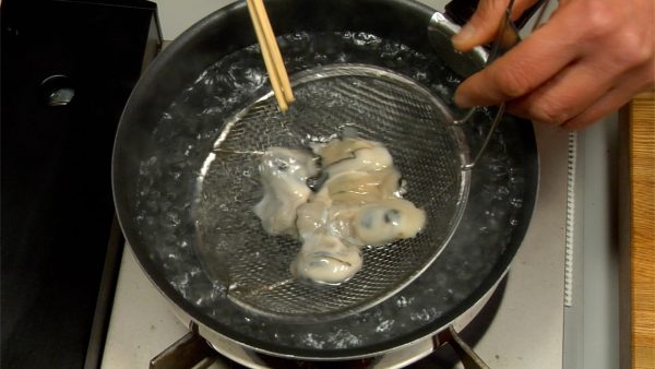Submerge the wire sieve in the boiling water and gently stir the oysters with a set of kitchen chopsticks.
