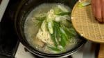 Ajoutez les nouilles udon avec le poireau. Détachez les nouilles avec des baguettes de cuisine.