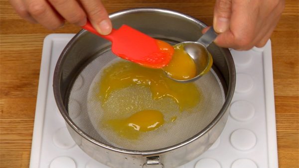 Flip the strainer over. Gather 1 tablespoonful of the mango purée with a spatula.