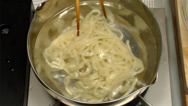 Let's cook the udon noodles. Drop the frozen udon noodles into a large pot of boiling water. After 30 seconds, separate the noodles with chopsticks and remove with a wire sieve.