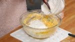 Agrega 1/3 del harina de pastel. Toscamente combina de manera envolvente la mezcla, pero ten cuidado de no sobre mezclar el batido.