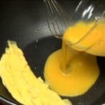 Place the rolled egg on the other side of the pan. Coat the surface with oil again and add a quarter of the egg mixture.