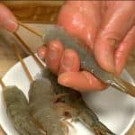 Stick the bamboo skewer into the body of the prawn, making it straight.