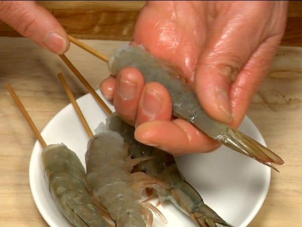 Stick the bamboo skewer into the body of the prawn, making it straight.