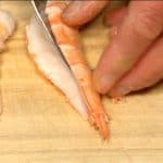 Remove the skewer from the prawn. Peel the shell and remove the tail. Cut the prawn in half lengthwise.
