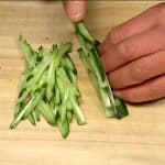 Coupez l'oignon nouveau en tranches très fines. Retirez la partie racine des pousses de radis kaiware. Coupez le concombre en tranches fines en diagonale et coupez-le en lamelles fines. 