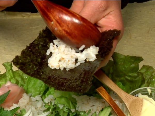 Here is an example of how to eat Temaki Sushi. Place a small amount of the sushi rice on a sheet of toasted nori.