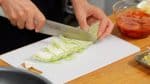 Trong lúc đó, chúng tâ sẽ cắt các nguyên liệu. Tạo một đường cắt vào lõi bắp cải và tách các lá ra. Cắt lá thành các dải 2cm (0,8 inch).