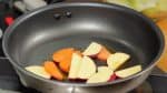 ではチーズタッカルビを焼きます。フライパンを熱しごま油を入れます。さつまいも、人参を炒めます。