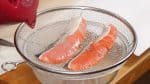 Pour hot water over the skin of the salmon. This will make it easy to remove the scales and also get rid of the fishy odor.