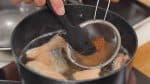 Hòa tân tương miso trong nước dùng. Dùng lưới lọc sẽ giúp hòa tan các cục tương miso trong nước súp.