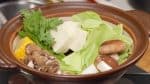 Préparez l'Ishikari Nabe. Arrangez les légumes dans un fait-tout en terre cuite avant (chou, shiitake, poireau, épi de maïs, shungiku et tofu).