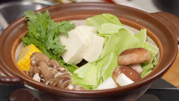 Let’s make the Ishikari Nabe. Arrange the vegetables in a pot beforehand. (cabbage, shiitake, long green onion, ear of corn, shungiku and tofu)