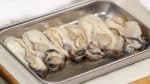 Next, combine the soy sauce and the sake in a tray. Add the oysters and coat them with the seasoning.