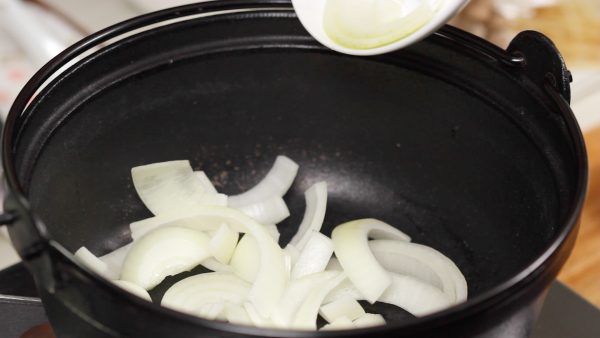 Mari membuat kimchi nabe. Sebarkan irisan bawang bombay di dasar panci.