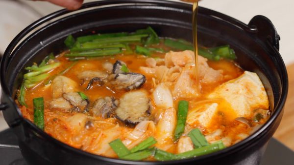 Tambahkan irisan kucai. Tuangkan minyak wijen dan masak tiram hingga matang. Sekarang, kimchi nabe siap dihidangkan.