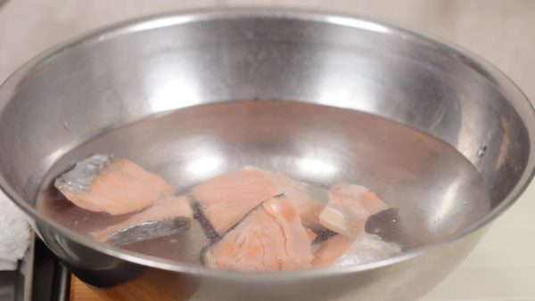When the surface turns slightly white, remove and place the pieces into a bowl of cold water. Rinse the salmon thoroughly and carefully remove the scales.