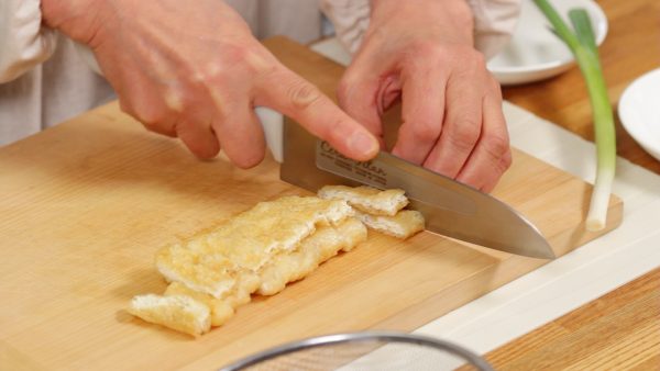 Cut the aburaage in half lengthwise. Stack the halves on top of each other and cut the aburaage into 1cm (0.4") pieces. After cutting the aburaage, be sure to clean the oil from the cutting board and the blade of the knife.