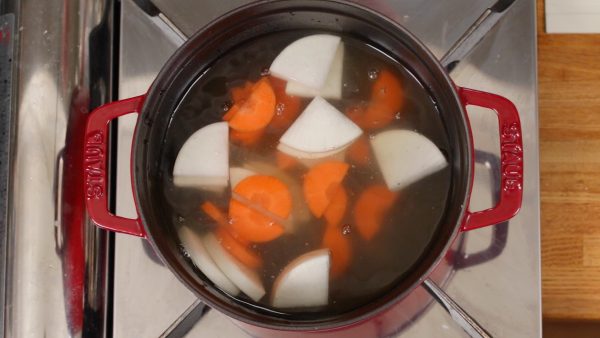 Let's make the Kasujiru. Place the dashi stock in a pot and add the daikon radish and carrot.
