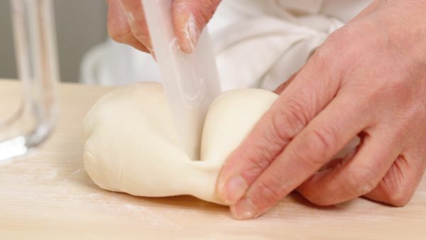 Remove the dough from the work bowl. Dust a cutting board with bread flour and place the dough onto it. Halve the dough with a scraper.