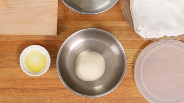 Next, coat the bottom of a bowl with olive oil and place the dough piece into it. Repeat the process for the other half of the dough. If a larger bowl is available, you can place both dough balls in the same bowl.