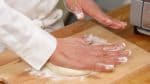 Polvilhe a massa com farinha de trigo. Achate a massa com a palma da mão mas evite pressionar as bordas.