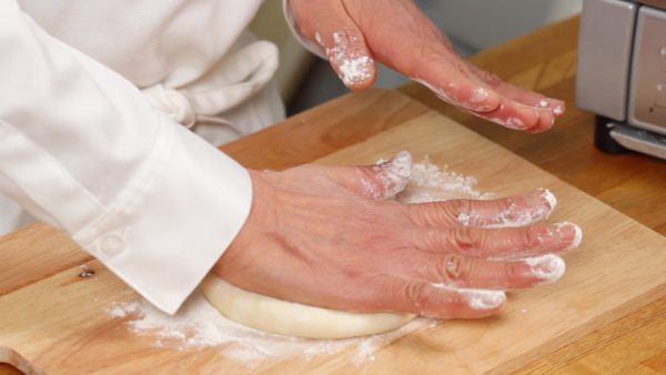 Dust the dough with bread flour. Flatten the dough with your palm but avoid pressing the edges.