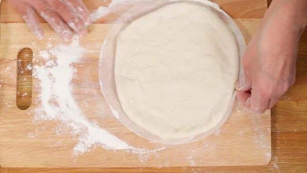 Then, place the dough onto a sheet of round parchment paper.
