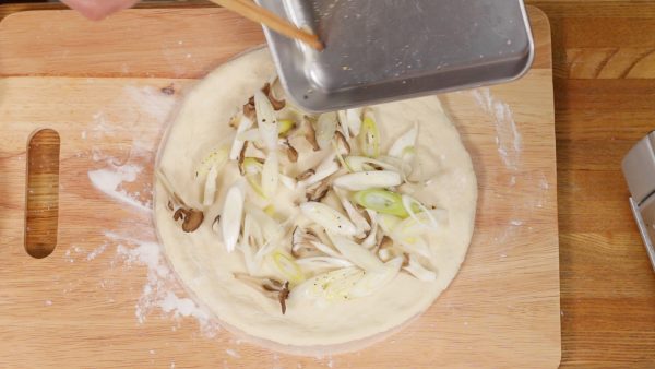 Then, distribute the onion and mushrooms onto the dough. Alternatively, shiitake, shimeji or king oyster mushrooms can be used.
