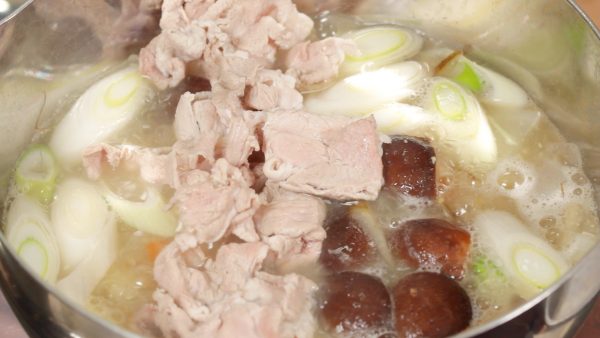 When the ingredients are almost cooked, place the pork slices into the pot.