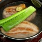 Pour in the water until it covers the top of the pork. Add the green part of the long green onion and the crushed ginger root.