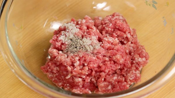 Next, place the ground beef and pork in a bowl and add the salt and pepper. With your hand, squish the meat to mix.