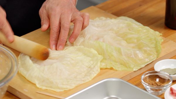 Let's wrap the meat filling. With a rolling pin, pound the firm bottom part of the cabbage leaves to soften. This will make it easy to wrap the filling, but be careful not to break the leaves.