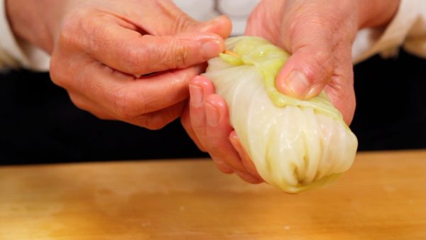 Fasten the edge of the leaf with a bamboo stick. You can also tie the cabbage roll using a piece of long pasta.