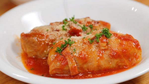 Ladle the sauce over the cabbage rolls. Finally, sprinkle on grated Parmesan cheese and chopped parsley leaves.