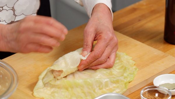 Next, cover it with the bottom part of the large cabbage leaf. Fold both sides of the large leaf.