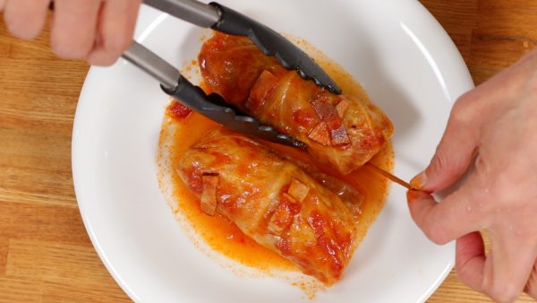 Using tongs, place 2 cabbage rolls onto a plate. Don't forget to remove the bamboo sticks.