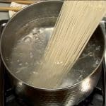 Place a bundle of soba noodles in a large pot of boiling water. Gently separate the noodles evenly in boiling water.