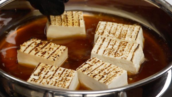 Place the yaki dofu into the pot. Turn the burner to medium heat. Then, flip the tofu over, heating it evenly.