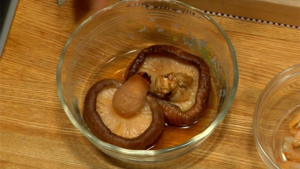 Vi börjar med att skära ingredienserna för Nikuman. Dessa torkade svamparna är för-tvättade och uppblött i en kyl över natten. Kläm ut vattnet från shiitake svampen.