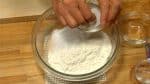 让我们为肉包子做面团。 在通用面粉中加入发酵粉、速溶酵母、糖和盐。 用勺子轻轻搅拌。