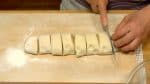 Выложите тесто на присыпанную мукой поверхность и раскатайте в цилиндр. Тесто разрезать на 8 равных частей.