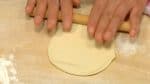 Chúng tôi sẽ cuốn nhân thịt vào bột. Để mặt mềm của bột lên bề mặt và nhấn nó xuống bằng tay bạn. Cuộn bột dùng cây cán bột đến khi đường kính nó khoảng 10 cm (4 inch).