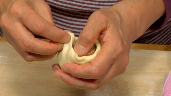 Gather the edges of the dough up to the center while making the pleats.
