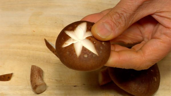 Coupez les pieds des champignons shiitake. Faites des entailles  en forme d'étoile sur les chapeaux des champignons.