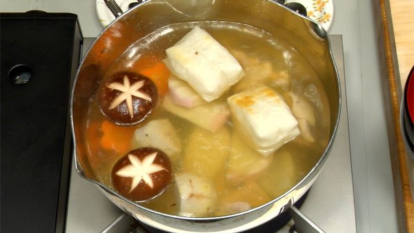 Quand le poulet est légèrement coloré, placez les champignons shiitake, le radis daikon, la carotte, le taro et le kamaboko dans la soupe pour les réchauffer. Réchauffez le kirimochi grillé dans la soupe. 